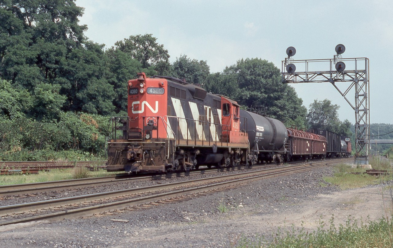 Canadian National GP9 4380 hammers west through Bayview Jct. at the head of a short six car consist. Built by GMD in London, Ontario as CN 4125 in 1957 she would carry her original number until 1984. Rebuilt as a GP9RM (GP9u) by CN’s Pointe St. Charles facility in 1991 and renumbered 7021, she would ultimately be retired following a wreck at Coteau-du-Lac on September 5th 1997.