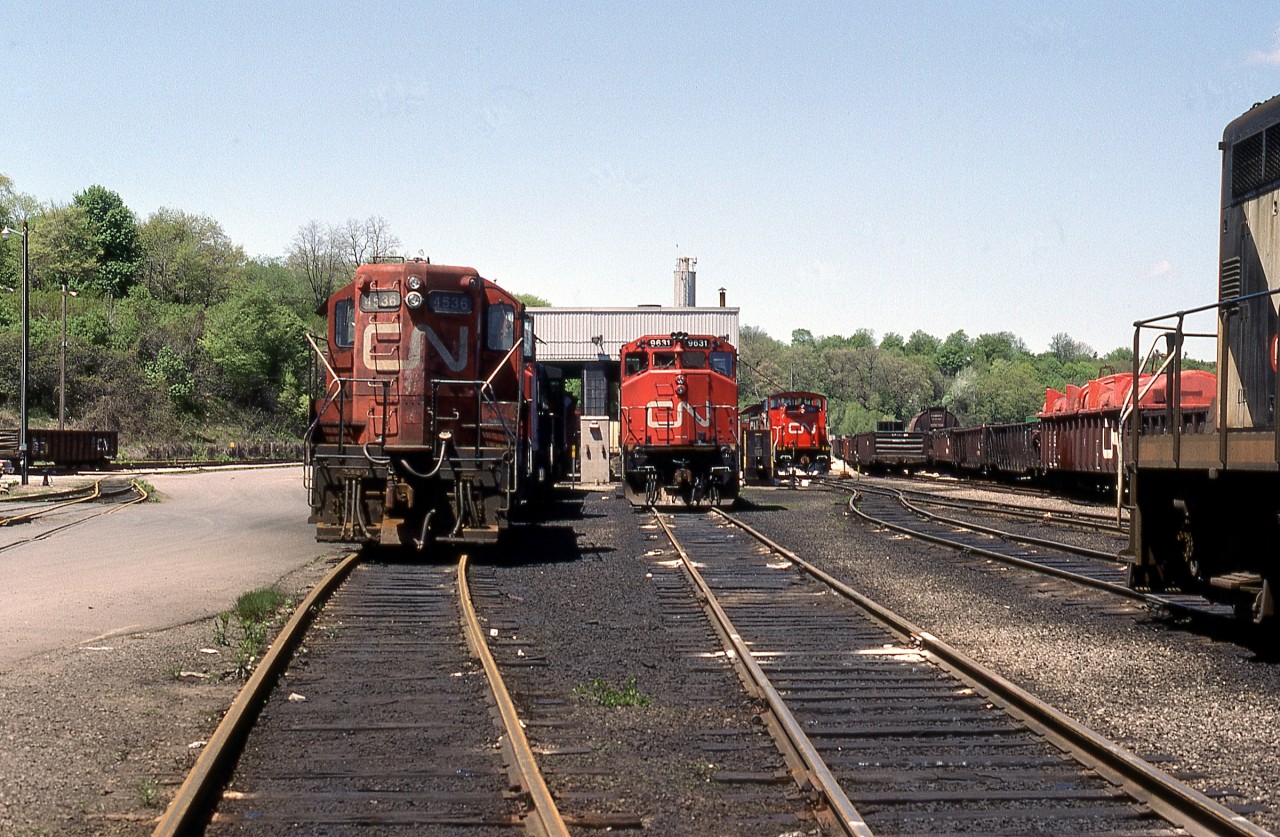 A mid-spring Sunday afternoon reveals a potpourri of all GMD power assembled at CN’s Hamilton waterfront Stuart Street Yard facility. Left to right are GP9 4536, GP40-2L (W) 9631, freshly rebuilt GMD1u 1411 and mostly out of frame GP9 4537. Origin and disposition of the assortment as follows:

•	GMD1u 1411 – built by GMD in 1958 as GMD1 1009, rebuilt by Pointe St. Charles as GMD1u 1411 in 1989, retired in 2006.
•	GP9 4536 – built by GMD in 1957, rebuilt by AMF (Atelier Montreal Facility) as GP9u (GP9RM) 7053 in 1992, retired in 2010.
•	GP9 4537 – built by GMD in 1957, rebuilt by AMF (Atelier Montreal Facility) as GP9u (GP9RM) 7071 in 1992, still in service.
•	GP40-2L (W) 9631 – built by GMD in 1975, retired and sold to Watco in 2004, renumbered to WAMX 4021.

Recently announced Metrolinx plans call for the shop building to be razed in order to provide a new right of way related to expanded, all day GO Transit service.