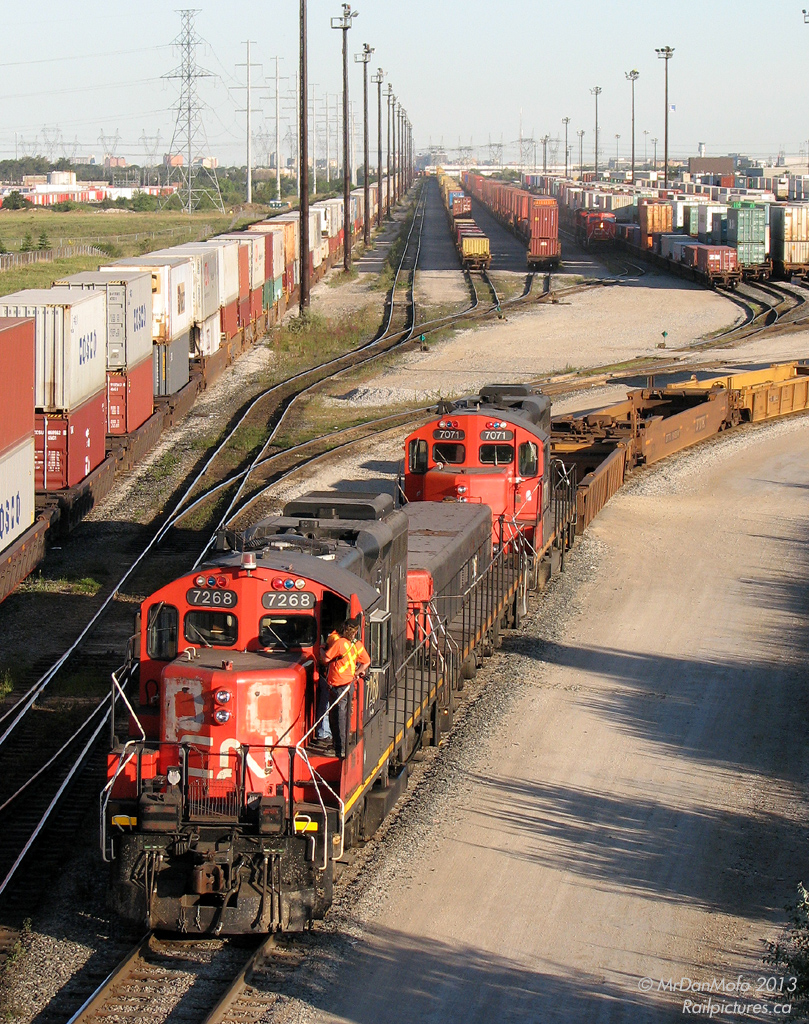 Railroading takes place in all elements: rain, sleet, snow, and sometimes when it's warm and sunny. On a warm summer evening, Canadian National GP9RM's 7268 & 7071 chug around the yard with booster slug 219, working double stacks and well cars at the north end of CN's Brampton Intermodal Terminal at Queen Street.