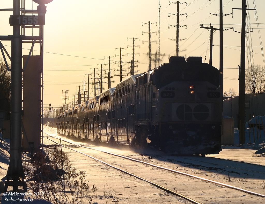 After a big early morning derailment just east of the Credit River closed the entire line at 2am, GO service on the Georgetown line was severely crippled all day. Morning trains were cancelled, GO bus service was a mess due to 15 centemetres of snowfall, and evening train service was reduced (2 instead of 4 trains) and only ran as far as Mount Pleasant Station, with passengers going further west having to hop GO shuttle buses to their destinations. CN maintenance crews were all over the derailment site, and Hulcher crews with side-boom tractors and excavators were busy cleaning up the mess and cutting up CN #394's damaged cars at the Credit. The biggest impact however was that the otherwise busy CN Halton Sub was quiet for most of the day, as no freight or passenger traffic could pass. Evidence of this litters the champaign-lit ground this evening: it's 5:30pm, and the powdery snow being kicked up hasn't been touched by any other train since the derailment 15 hours ago.After dropping off its load of evening commuters at Mount Pleasant just east of the derailment site, GO #205 highballs eastbound back to Toronto. F59PH class-unit 520 leads 10 empty commuter cars through downtown Brampton, slamming over the diamond at Mile 15.5 on the north track. Not being able to get to and tie down at Georgetown overnight, any GO's had to deadhead back to Toronto and return deadhead in the morning when the track was finally cleared.