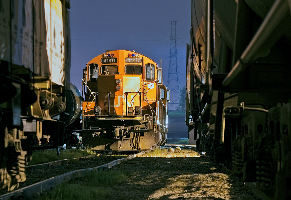 Tucked away for the morning into track A016 at Oshawa Yard, 4140 and 7046 rest after a hard nights work on 546. The power will be used later on for a beltpack yard job which services GM's Oshawa Car Plant, local customers and the building of 546's train. In the back, CN 309 pulls down the lead towards B yard for a 4 car tail end set off. Taken on CN property by a CN employee with PPE gear on.