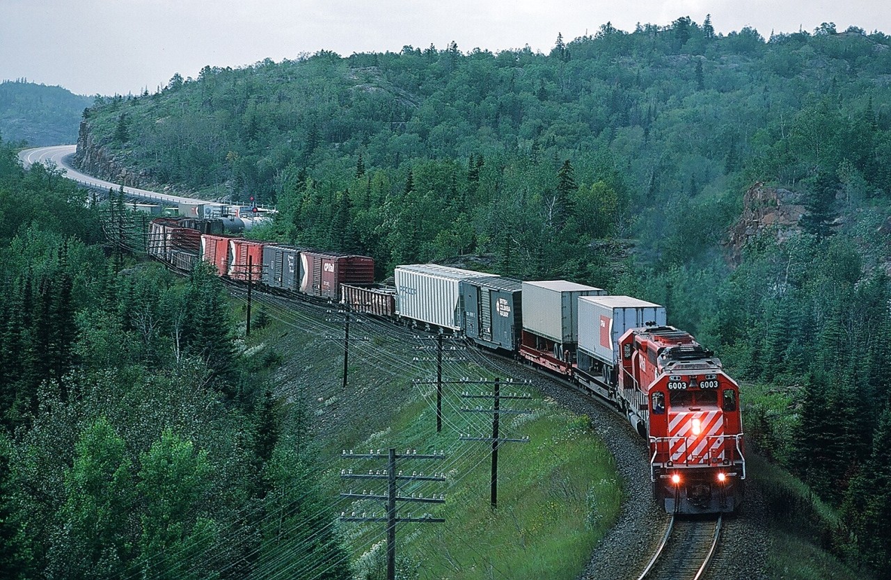 Ah.....Summer North of  Superior.....when track occupancies ( blocks ) limit daylight train operations....where any operating train is a celebration....August 30, 1984  CP Rail 6003  ( with  5528 ) East squeals through the curves near Mile  74.0 (?) Heron Bay Subdivision. Note the now rare freight mix CP Rail  TOFC's, CPR brown box, CP Rail boxes, BCR box. Kodachrome by S. Danko.

What's interesting: SD-40 CP 5528 sold to Dakota, Minnesota & Eastern in 2000 now DME 6092.


More Northern Ontario:

   exceptional  

   end of train device  

    rare sight