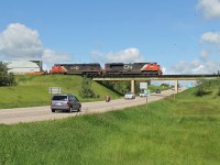 SD 70M-2 8020 and DASH 8-40CM 2440 cross a busy Hyw 37 on the Vegreville Sub at Fort Saskatchewan