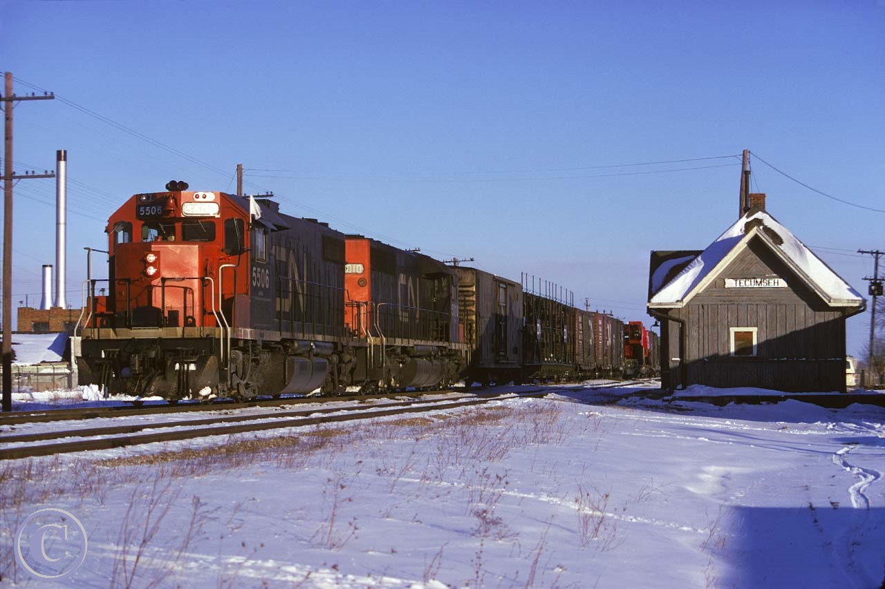CN 5506 and 5010 with train 435 pass the old Tecumseh station enroute to the Boat Yard in Windsor. The Tecumseh station was built in 1854 and was the telegraph and post office and later had the only telephone in town.  It was used to transport tanks, trucks, and jeeps in WWII. The station was used until 1967 and was moved to the nearby Canadian Transportation Museum and Heritage Village in 1976.