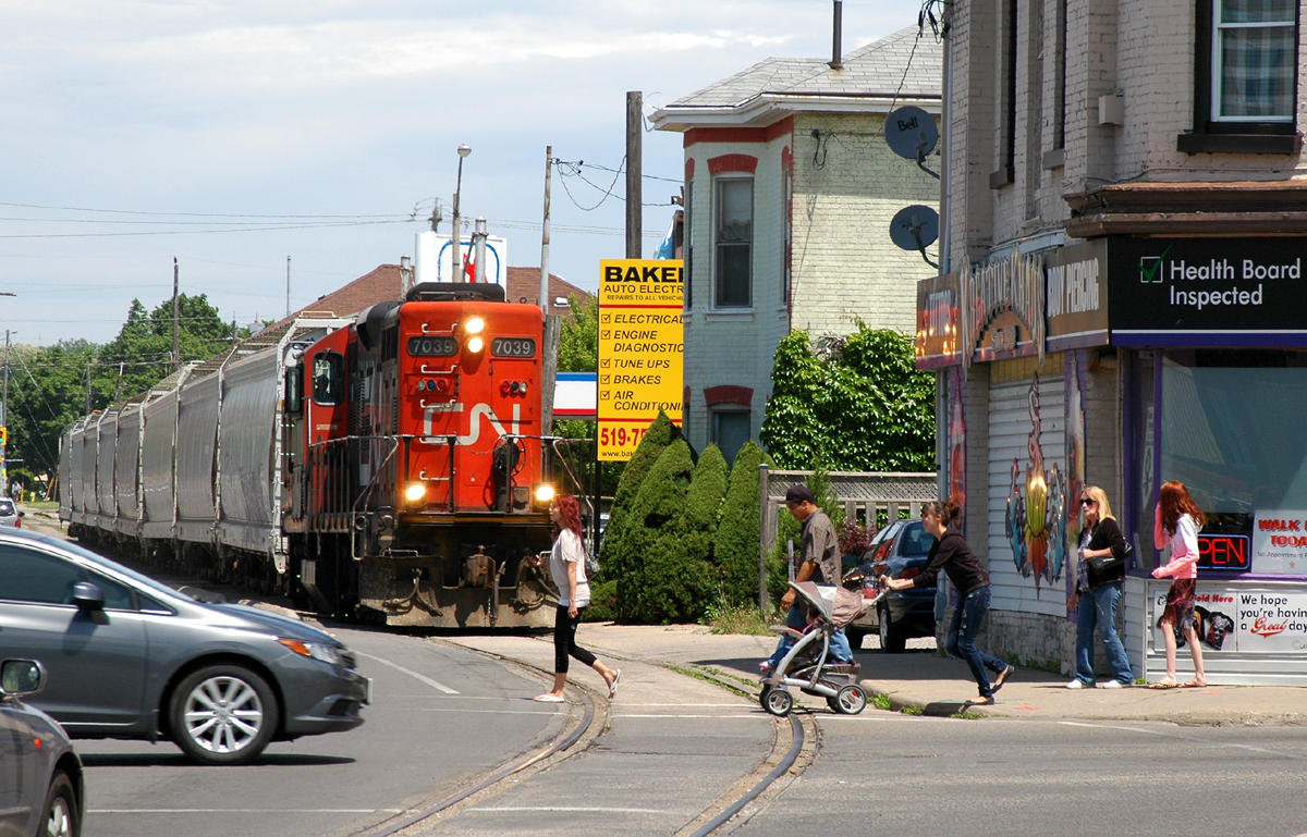 Pedestrian's and traffic go about business as CN 580 creeps up to the corner of Colborne Street