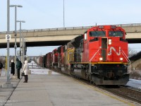 <b><i>Right Time, Wrong Train.</i></b> <br><br> Creatures of habit, early morning commuters await the arrival of their Toronto-bound GO train, "the 8:08 from Bramalea" (formally known as train #210 from Georgetown), on the middle platform, on the south track, just as they do every morning. Except today, things are a little different. It's now 8:14am and the usual GO that was supposed to arrive 6 minutes ago is a no-show, replaced by a long CN freight train rumbling through on the opposite side of the platform.  <br><br> Yup, you guessed it: the CN Rail Traffic Controller, for whatever reason, held the GO at Brampton and ran this monster of a CN #394 ahead on the single track section. Motoring east on the north track with 15,400 horsepower on the head end, shiny CN SD70M-2's 8828 & 8840, yellow UP SD60M 2273, and black IC 6050 muscle their train eastward to Concord, while anxious commuters peer down the track looking for the headlight of their GO train. After the tail end of the freight clears, the GO will get the green light, and arrive at Bramalea 10 minutes late to pick everyone up. <br><br> It's business as usual on the railway, and just another day taking the GO into The Big Smoke.