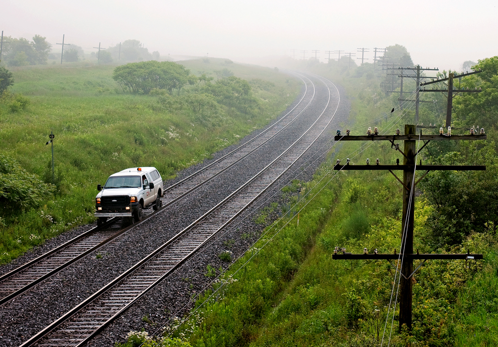 No train in sight to make the scene ? No problem, a hi-rail will do... Fog rolls in off Lake Ontario after a rain storm meanwhile an engineering foreman does a track inspection of the north track between trains.