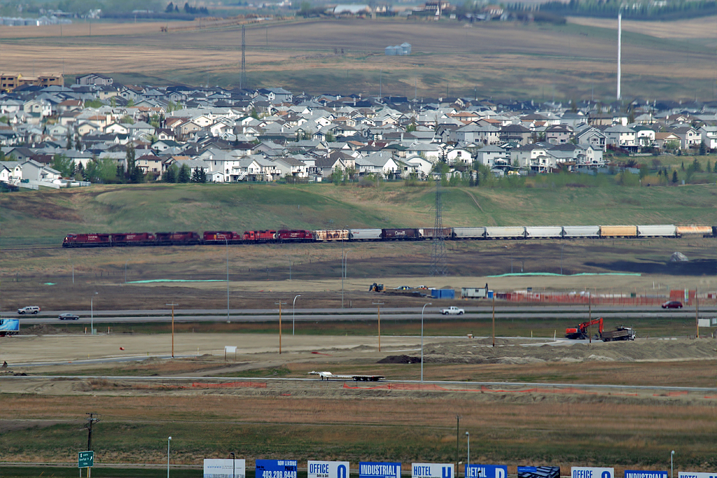 In a view from the tower at Calgary airport, 2 ES44's, 2 AC4400's, and SD40-2 and 2 GP38's bring a long southbound into Calgary for a meet.