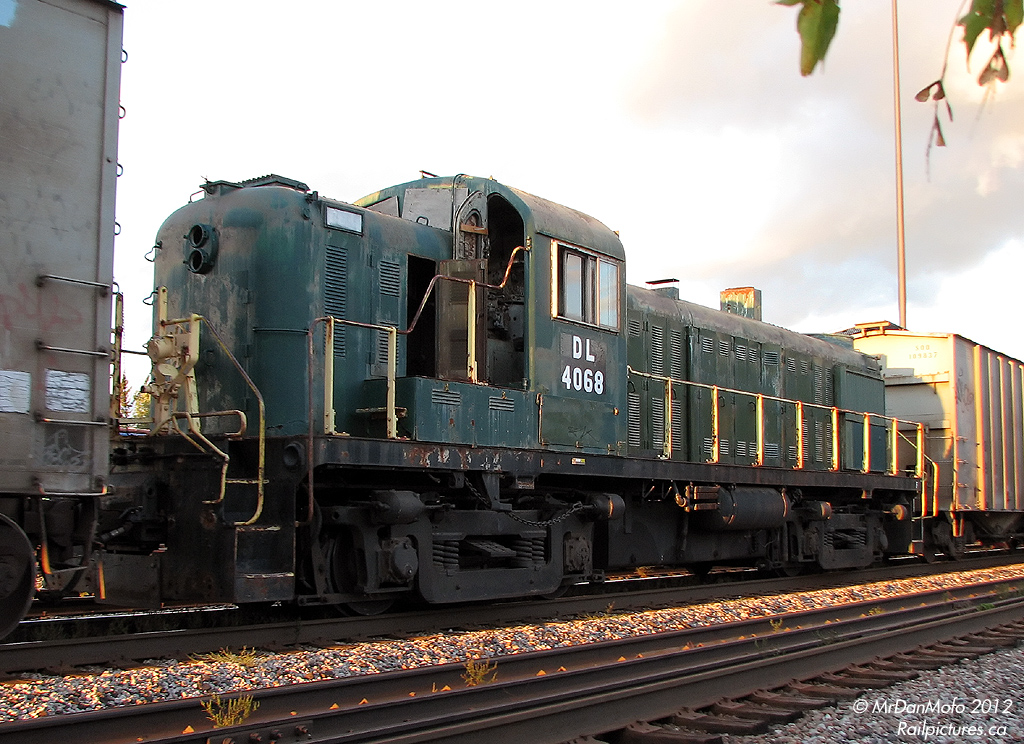 There's a funny story behind this photo. Delaware Lackawanna, a regional railroad with a major jones for purchasing old American Alco power, purchased this old former Delaware & Hudson RS3 from tourist operator York-Durham Heritage Railway. "DL 4068" arrived at CP's Agincourt Yard about a week or two ago, and basically fell off the radar since. Nobody knew when it was to leave or on what.  Fast forward to today: after being tipped off the first completed brand new GO Transit MP40PH-3C was sitting at Lambton/West Toronto yards awaiting delivery, the ever-adventurous photographer makes a second trip downtown in an attempt to catch a shot of it. Upon arriving on the scene, and heading trackside, he finds the crew of CP westbound #254 stopped and giving a roll-by to a passing eastbound near the yard area. Casually asking the crew if they've seen any new GO locomotives sitting around, one replies something along the lines of "No, but we've got some old locomotive in the train a few cars back". This was followed by a "Hmmm" moment, and then an "Ahhh!" upon looking down the train and realizing what it might be.  The crew then climbs back aboard their train and slowly gets it underway. Two cars down in-train was the dead RS3, beat up and ratty looking, heading for its new owner in the US to be rebuilt, repainted, and put back in service.  Alternate photo of the train near the yard.  (And I got the GO unit too, but we'll leave that for another day...)