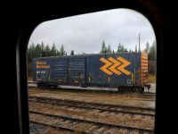 Seen through the vestibule window from the Polar Bear Express, Ontario Northland boxcar 2709 sits on one of the shop tracks in front of the old engine shed across from the station on a gloomy day in far, northeastern Ontario.