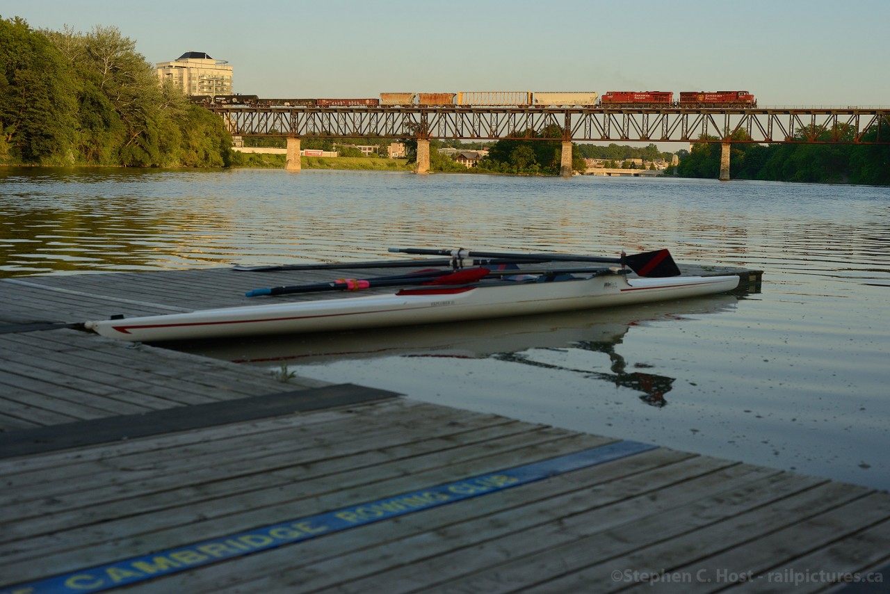 In the last rays of golden light, CP Train 255 crosses over the Grand River as the Cambridge Rowing Club members have just finished an evening on the water.