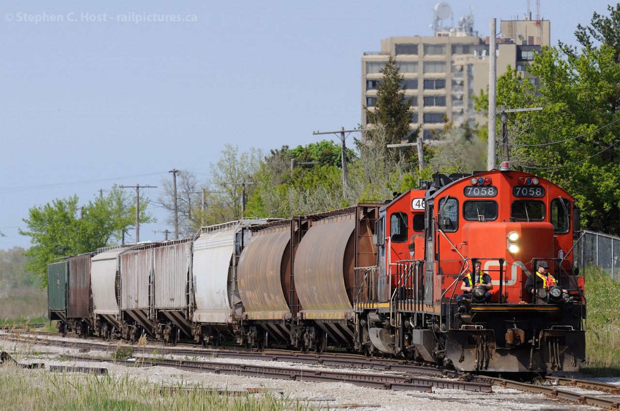 On a warm spring day, the crew is enjoying the breeze piloting their train through a busy area known for pedestrians. What remains of "E" yard - pictured -  was a staging point for ferrying cars across the St. Clair River (until 1995) and a CN/CSX interchange point (which still occurs, just rarely). Now it's used to support switching Imperial Oil (behind the photographer) and Cargill Elevators - at the end of the Point Edward spur. Some tracks have been disconnected and removed over the last couple of years as seen in this photo.
Here's a John Eull shot showing the yard during the busier ferry days - with a station on site: http://www.railpictures.ca/?attachment_id=4948