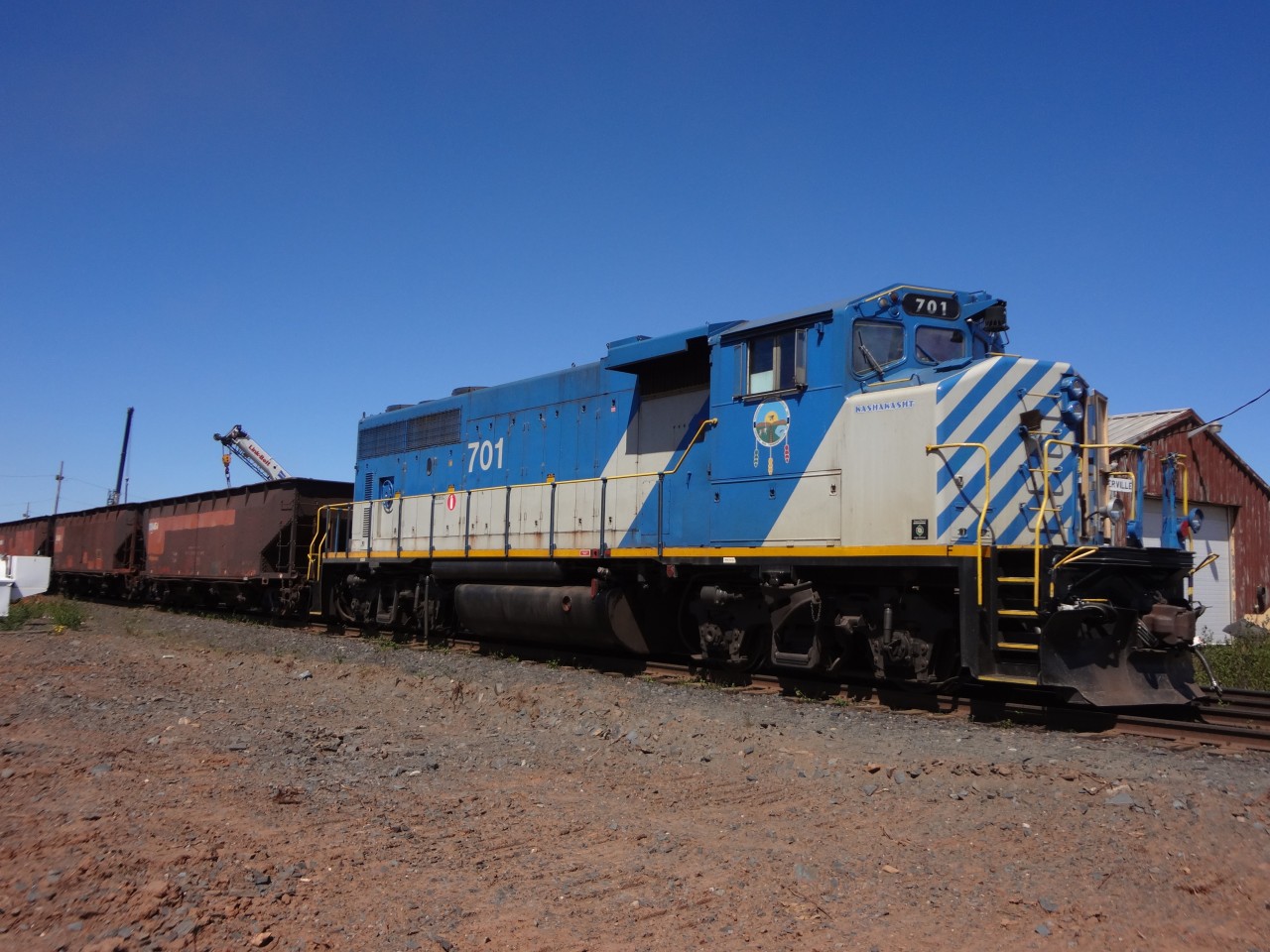 TSH 701 sits connected to a string of well used ballast cars in Schefferville yard on this pleasant early summer day.