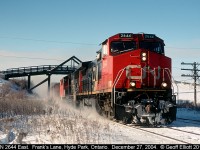 CN 2644 has an eastbound well in hand as it kicks up some fresh overnight snow.  2644 is passimg under the bridge for Frank's Lane just west of Hyde Park, Ontario.