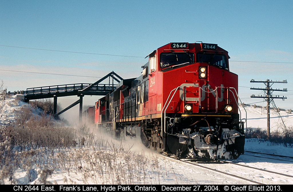 CN 2644 has an eastbound well in hand as it kicks up some fresh overnight snow.  2644 is passimg under the bridge for Frank's Lane just west of Hyde Park, Ontario.