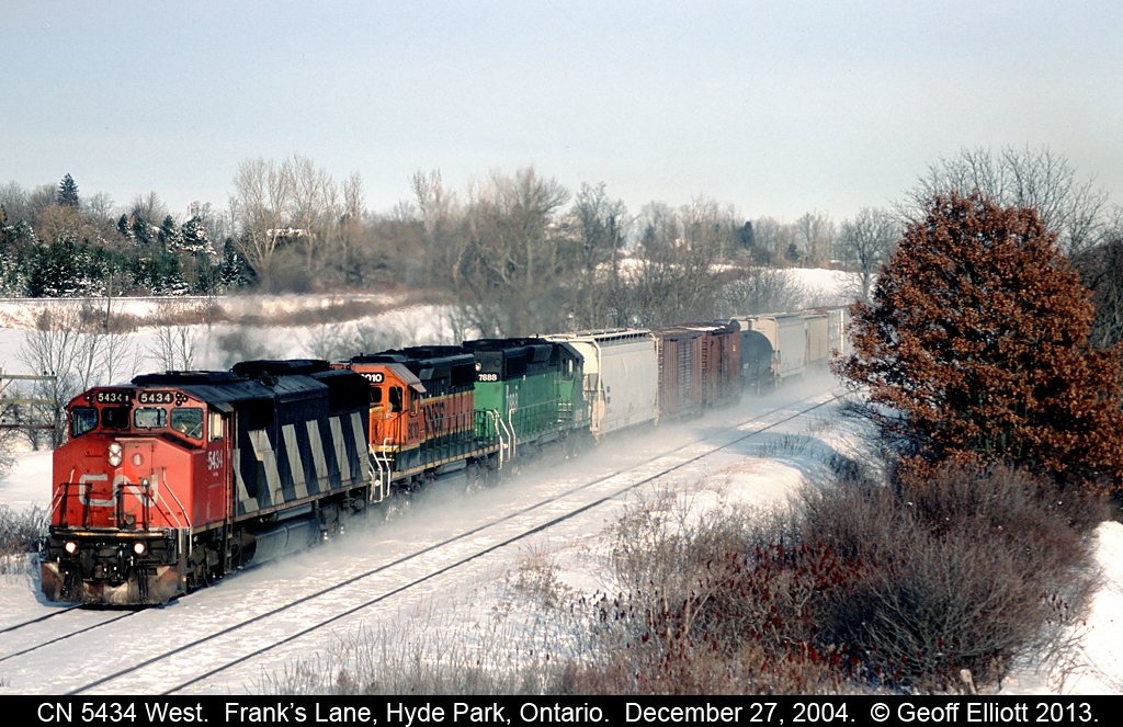 It's a couple days after Christmas 2004 and CN SD50F #5424 has 2 BNSF SD40-2's in tow as it kicks up some snow with a westbound mixed train at Frank's Lane just west of Hyde Park, Ontario.