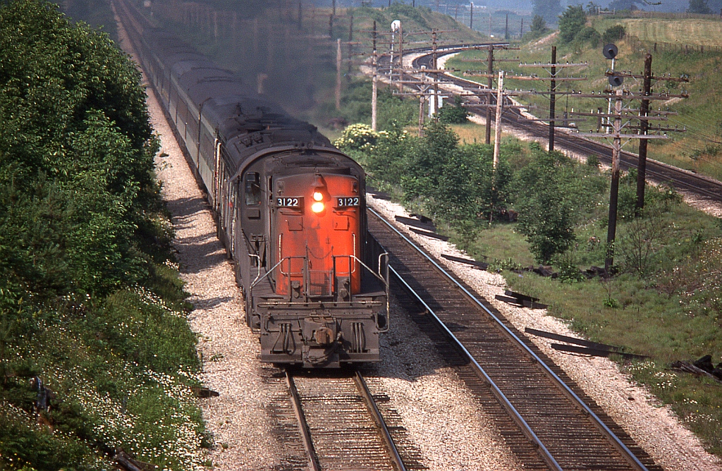 Speeding east with an MLW RS18, F9B and FPA4 leading the charge, an eastbound VIA-CN passenger train rolls through Hyde Park at Denfield Road, on its way to London. Looking carefully, one can pick out a few blue VIA-painted cars in consist. On the right in the background, east siding switch Lobo on CP's Windsor Sub can be seen.