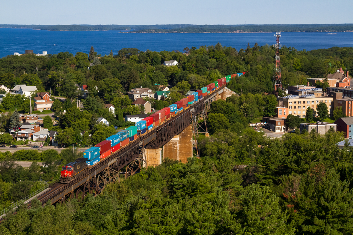 Arguably the best angle in all of Parry Sound, one can view the entire town and miles surrounding from atop the old fire tower, now observation tower. Growing up seeing photographs of Canadian Pacific passenger and freight trains crossing this magnificent bridge in various Canadian railroading books I have always wanted to capture a photo of my own from this location. Although Canadian Pacific no longer runs the trains similar to those captured in Greg McDonnell's book 'Stand Fast, Craigellachie!', for instance, and southbound trains no longer run over this bridge (because of a Directional Running agreement), one can still occasionally get lucky if either CN or CP runs a lengthy train requiring DPU assistance. This is exactly what occurred in this photo, on a crisp July morning, a huge difference compared to the hot and hazy weather days prior. CN Q103 is seen soaring high above town on the Seguin River Trestle with a hotshot stack train for the west coast, leading the train nearly a mile away is CN 8896, in the middle of the train is 2114 and doing the honours on the rear is CNIC 2698. This train would have a straight shot to St. Cloud over the DRZ section of track in central/northern Ontario.