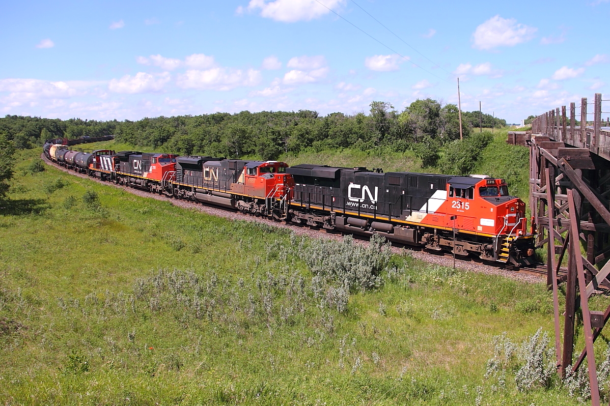 A CN manifest with four units. one being a GMD1, passes through Grant's Cut just east of Rivers.