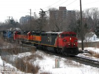 CN 394 heads through the downtown of multicultural Brampton with a rather multicultural lashup of foreign power on this gloomy day...
<br><br>
CN 2445 (C40-8M widebody) leads BNSF 6860 (ex-ATSF SD40-2), BNSF 333 (a rare-in-these-parts GP60B with no cab), CN 5366 (ex-UP SD40-2), NS 6777 (an SD60M still painted Conrail blue) and NS 8861 (a common black C40-9) past St. Mary's Catholic Cemetary, rolling over the Centre St. underpass by Peel Memorial Hospital. Taken before the line was double-tracked, Brampton East eliminated, and Peel interlocking moved west from Kennedy Rd.