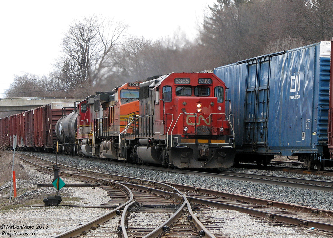 Back in the heyday of foreign power on CN, it seemed like there was something new everyday. If it wasn't a GCFX/WC leaser or an IC SD40, it was something from BNSF, UP, NS or even CSX running though behind CN power. It was often enough that railfans didn't bother staying out for the next train with a trailing UP SD70M or BNSF GE.  Typical for any interesting lashup, an overcast sky evens the lighting for CN #393, after meeting #392's headend (which had an NS GE trailing) at Georgetown Station, passing the lead into the GO commuter compound in the foreground. CN SD40-2 5365 leads BNSF "Pumpkin" Dash-9 4079 and BNSF GP60M 151, which was still in the warbonnet colours of original owner Santa Fe. This was the best shot of a tight situation, as stopped #392 obscured any shot from the station side, and a typical GO fence fudged any chance of a wider shot of this train and the power seconds later.  Reportedly ol' 151 had some engine trouble later that day and I believe they sent it back to Mac Yard on another freight. 4079 made another appearance a few days later on a CN #X392 with a BNSF SD40-2 snoot and IC SD40-2. FPON everywhere.