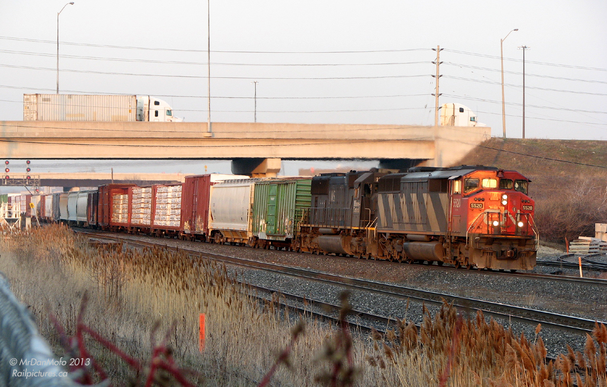 Rolling west into the sunset with a long freight in tow, CN #395 has just passed through the junction of the Halton and Weston Subs ("Halwest") and rumbles through Bramalea GO on the banked curve around the platform. CN SD60F 5520 and IC SD70 1005 lead the charge west to Georgetown, Milton, Burlington, and beyond.
