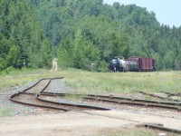 <a href="http://www.railpictures.ca/?attachment_id=10586">A short 9-car CN 571</a> trundles northward out of the desolation of the former Hawk Junction yard. The dirt track leading uphill in the background is the Algoma Central's former Michipicoten subdivision to Wawa and Michipicoten harbour, which was officially abandoned and the tracks lifted in 2000. The titular junction at Hawk Junction was once located just past the single remaining switch at left foreground leading to the south yard, which once commonly received trains of processed iron ore from the branch, but on this day saw only a lonely pulpwood flatcar. The grassy expanse to the right was once the main yard at Hawk Junction, where freight trains were made up and cars sorted. Now most of those tracks are completely ripped out, and the area becoming overgrown with grasses and weeds. (The track that disappears in the long grass in the centre of the image was formerly the ladded track for this part of the yard; you'll note a distinct lack of switchstands and points on this track today.) 
<br>
<br>
In it's heydey, Hawk Junction was a division point and the hub of operations on the Algoma Central Railway, seeing two daily regularly scheduled freights plus as required extras between Hawk Junction and Steelton yard in Sault Ste. Marie (in each direction), a daily freight between Hawk Junction and Hearst (again each way) and daily/as required ore trains on the branch to Wawa and Michipicoten Harbour as well as daily passenger service along the line. Today, the yard is barely more than a passing siding and a couple of set-out tracks, and both passenger and freight traffic is down to a thrice-weekly service. That little 9 car local trundling sure is a far cry from what once was.