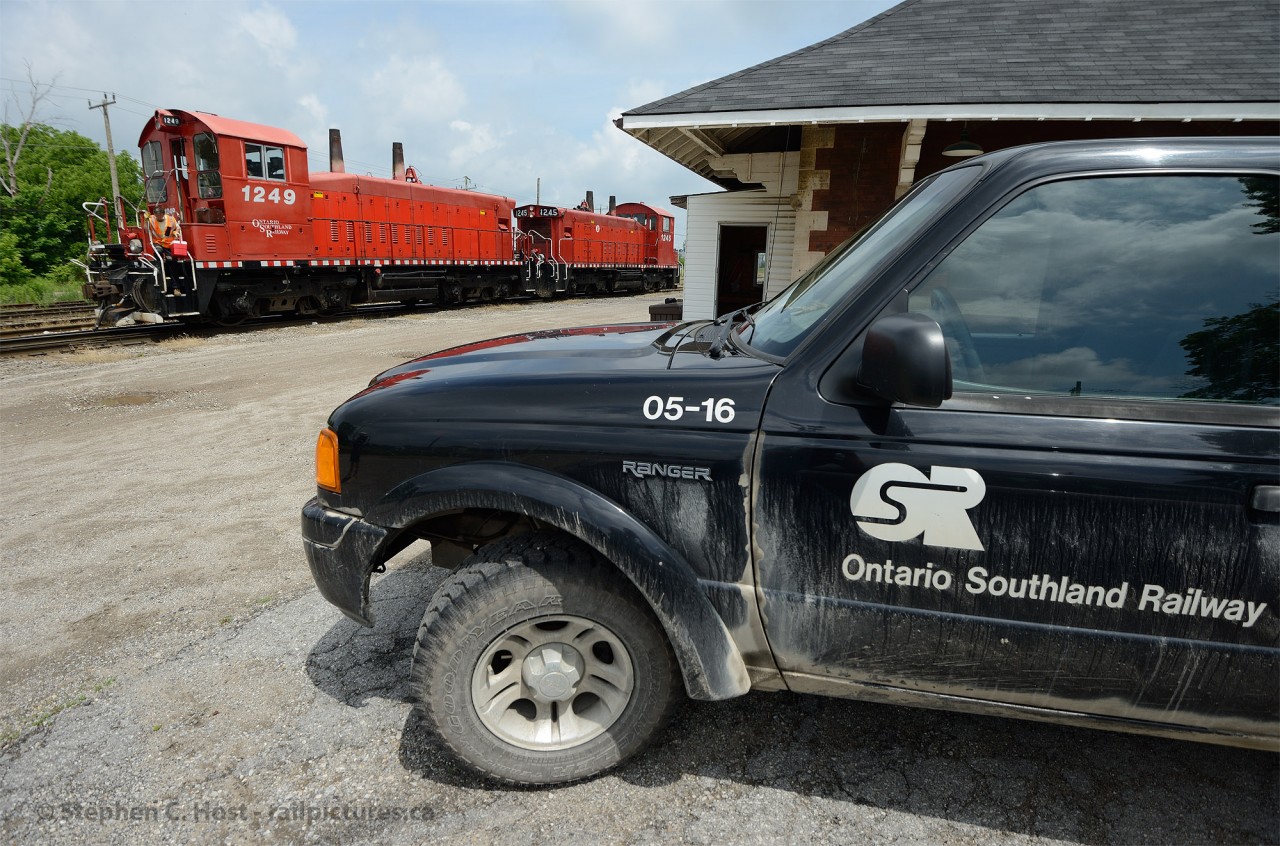 Framed above an Ontario Southland Railway Truck - a pair of pups sit at the Woodstock CP Station while crew is getting off with lunch to eat and print paperwork. The crew just arrived with cars from St. Thomas and Putnam and placed the train in the yard with ease.