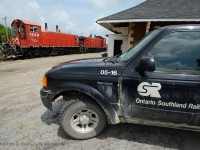 Framed above an Ontario Southland Railway Truck - a pair of pups sit at the Woodstock CP Station while crew is getting off with lunch to eat and print paperwork. The crew just arrived with cars from St. Thomas and Putnam and placed the train in the yard with ease.