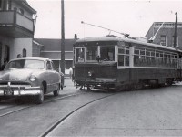 Street car operations in Cornwall ended in July 1949 and most passenger carrying equipment was scrapped shortly thereafter.  This car, 29, which had started its working life in Fort Worth, Texas and arrived in Cornwall in 1939, survived somewhat longer and was made available by a cooperative management for fantrips over the remaining and still extensive network of track, with electric overhead intact, devoted to the CSR’s freight operations.  This scene illustrates one of the risks of operating such an excursion on a Sunday when freight movements normally took the day off.  After some delay the impasse was resolved and 29 completed its left turn from Marlborough Street onto William Street.