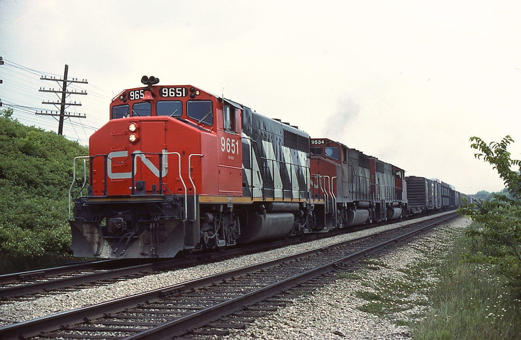 CN 9651, 9534, and another GP40-2L/W head through Hyde Park on a freight, around Mile 6 of the Strathroy Sub outside of London.