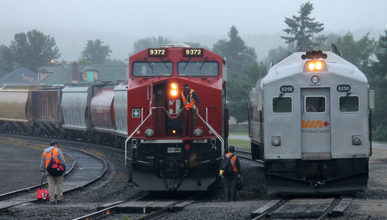 This Friday morning [26 July] in White River, Ontario dawns with rain; but by 0900, the time VIA 186 is set for departure back to Capreol and Sudbury, the steady rain has become a light mist. Once the half dozen passengers had boarded by the former station, the 2 car train – VIA 6250 / VIA 6105 proceeded eastward on the main track a short ways and stopped adjacent to the maintenance-of-way buildings where several CP employees loaded supplies into the baggage car. At the same time eastbound #112 – cp9372 – arrived and stopped for the crew change.  Which train headed east first?? VIA 186, of course!!