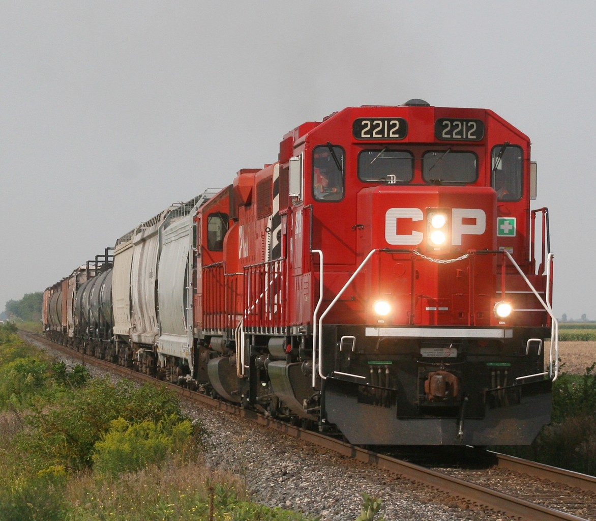 CP T29 heads eastbound through Drake Road, led by CP 2212, a new GP20-ECO unit, and GP38-2 #3015.