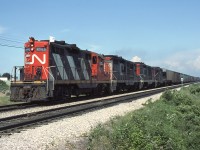 With a lone white flag flapping away, CN 4585 leads a nice four-pack of GMD GP9's hauling an extra freight through Hyde Park. The trailing 3 units are still in the CN noodle scheme (red ends, black carbody, white frame, big CN on hood sides), compared to the 4585 in the newer "zebra" livery featuring red ends, nose and cab, yellow reflective frame striping, CN noodles at the ends and white carbody striping along the hood sides.

<i>* Exact location unknown, possibly westbound at Hyde Park Road grade crossing.</i>