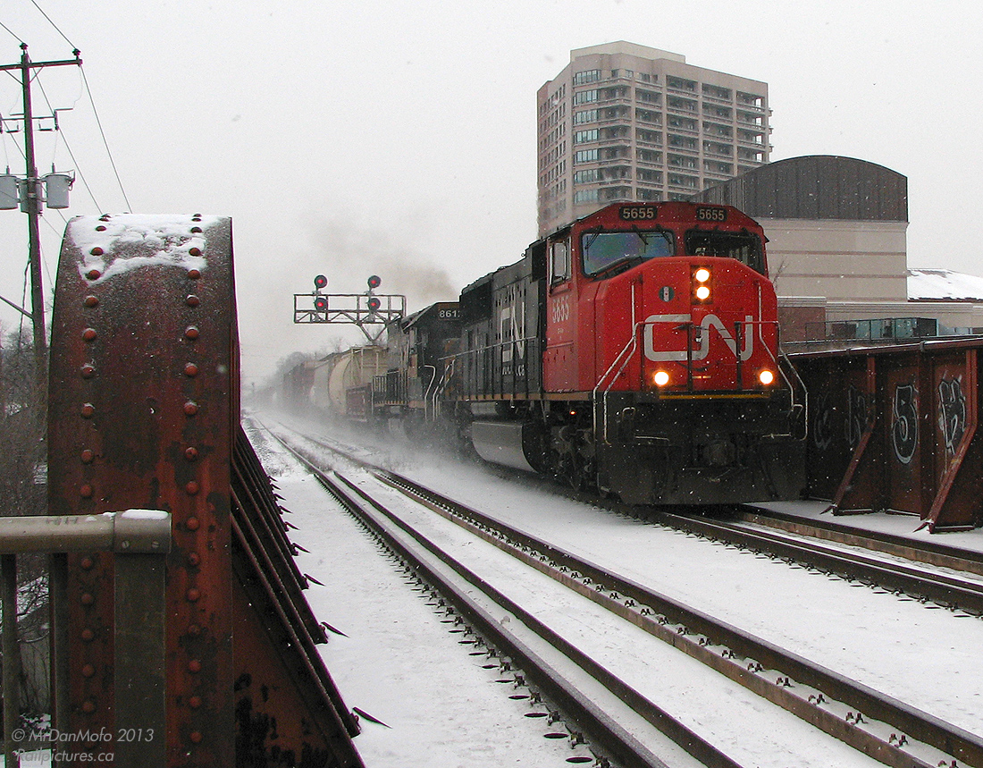 It was a cold winter morning in Southern Ontario when a Denver & Rio Grande Western tunnel motor (albeit patched, but still in full D&RGW colours) was due to head back out on a freight, which had came in on an eastbound the previous night at CN's MacMillan Yard. Having arrived at the station dark and early in the morning (06:30 hrs) in hopes of catching it before my morning train to Toronto, it became a waiting game as various CN freights juggled track time with the 4 morning GO trains and VIA. All the while text messages between people in the know were exchanged, and it was determined it was going to be going out on #391 or possibly #399, but #391 came and went with only a UP SD70M trailing.

At 07:59 a decision had to be made, and the photographer reluctantly stayed on the cold snowy platform as the last GO train to Toronto pulled out of the station without him. Unheated platform waiting shelters are very ineffective in the cold, but there wasn't much choice for one not wanting to stray too far from the tracks - lest his pray show up while he was waiting in the station with no clear line of sight, or up the street buying some warm pizza at Gusto's.

Finally, a headlight poked up on the snowy horizon, and back out into the snow we go. CN #399 with SD75I 5655 and UP "DRGW" SD40T-2 8612 thunder over the steel bridge above Main Street, heading west through downtown Brampton in the falling snow. The trailing unit shot was a touch blurred, but this one turned out okay considering.

The next step? Hop on a GO bus for a one-hour express trip to York Mills and the subway downtown, 3 hours after arriving, but with a DRGW in the camera.