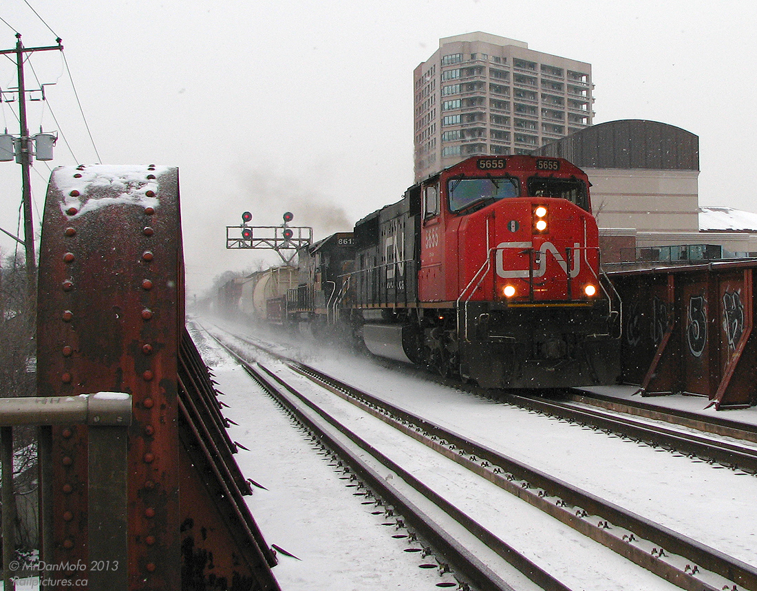 It was a cold winter morning in Southern Ontario when a Denver & Rio Grande Western tunnel motor (albeit patched, but still in full D&RGW colours) was due to head back out on a freight, which had came in on an eastbound the previous night at CN's MacMillan Yard. Having arrived at the station dark and early in the morning (06:30 hrs) in hopes of catching it before my morning train to Toronto, it became a waiting game as various CN freights juggled track time with the 4 morning GO trains and VIA. All the while text messages between people in the know were exchanged, and it was determined it was going to be going out on #391 or possibly #399, but #391 came and went with only a UP SD70M trailing.

At 07:59 a decision had to be made, and the photographer reluctantly stayed on the cold snowy platform as the last GO train to Toronto pulled out of the station without him. Unheated platform waiting shelters are very ineffective in the cold, but there wasn't much choice for one not wanting to stray too far from the tracks - lest his pray show up while he was waiting in the station with no clear line of sight, or up the street buying some warm pizza at Gusto's.

Finally, a headlight poked up on the snowy horizon, and back out into the snow we go. CN #399 with SD75I 5655 and UP "DRGW" SD40T-2 8612 thunder over the steel bridge above Main Street, heading west through downtown Brampton in the falling snow. The trailing unit shot was a touch blurred, but this one turned out okay considering.

The next step? Hop on a GO bus for a one-hour express trip to York Mills and the subway downtown, 3 hours after arriving, but with a DRGW in the camera.