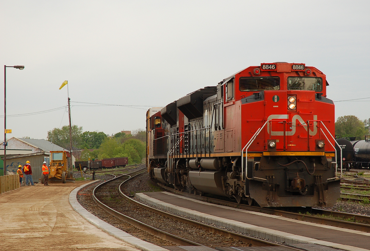 A crew from Brantco Paving works at grading the VIA platform as CN 8846 - CN 8835 lead an eastbound past