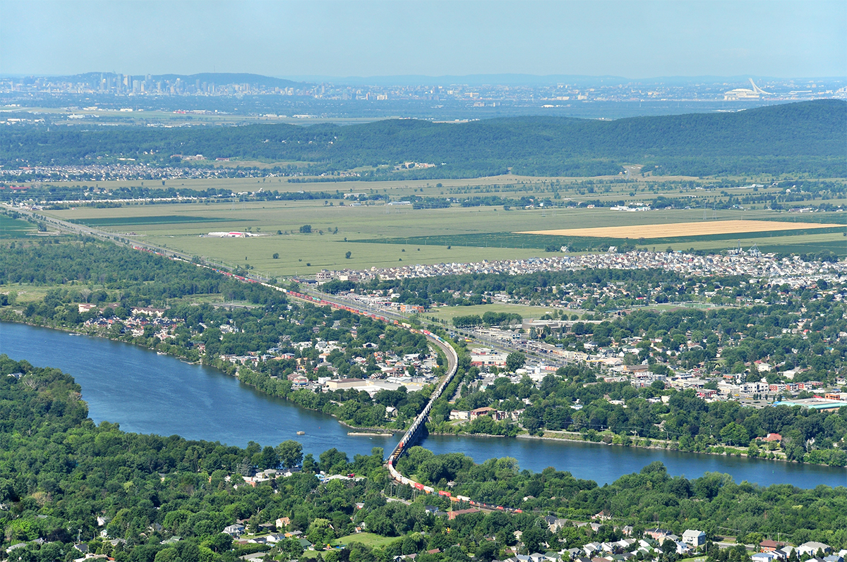 With a very long train, CN 120 pass over the Richelieu river. In the same picture, you can see Montreal downtown, the ''Mont-Royal'', the Olympic stadium of Montreal, a part of ''Mont-Saint-Bruno'' and few cities like Montreal, Saint-Basile-le-Grand, McMasterville, Beloeil, etc. The shot was taken on the top of the ''Mont-Saint-Hilaire'' with an elevation of 415m.