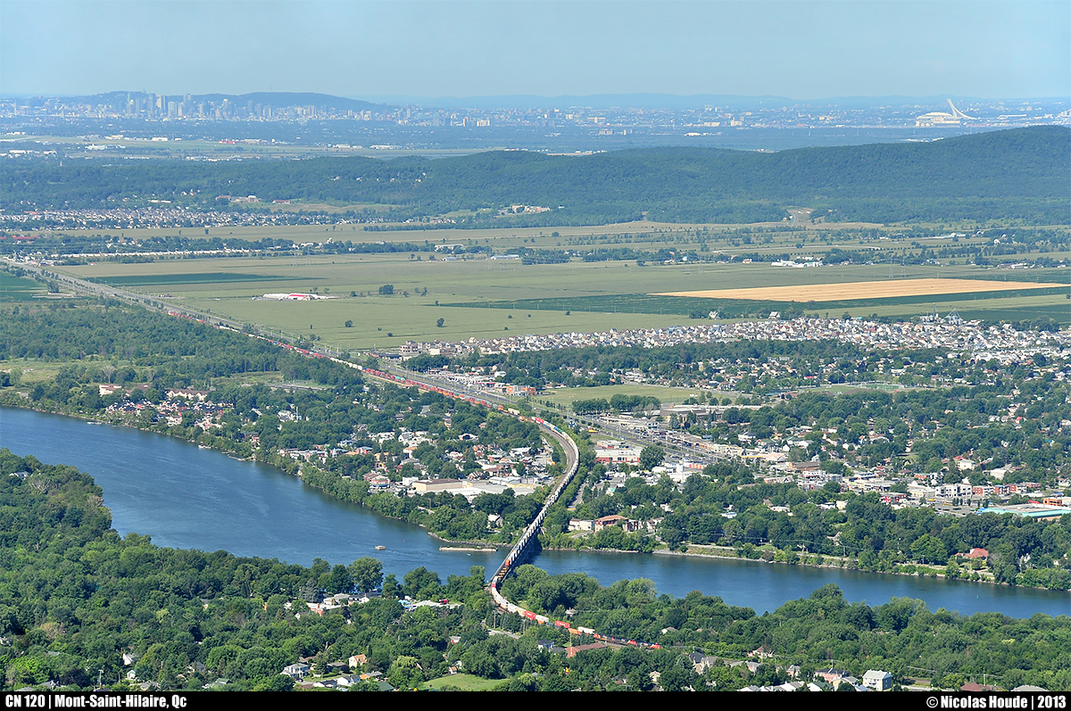 With a very long train, CN 120 pass over the Richelieu river. In the same picture, you can see Montreal downtown, the ''Mont-Royal'', the Olympic stadium of Montreal, a part of ''Mont-Saint-Bruno'' and few cities like Montreal, Saint-Basile-le-Grand, McMasterville, Beloeil, etc. The shot was taken on the top of the ''Mont-Saint-Hilaire'' with an elevation of 415m.