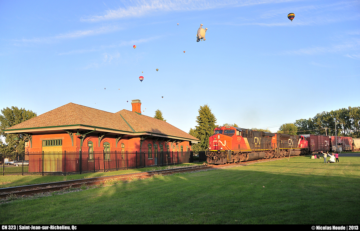 As the balloons starts to get up in the air, for the ''International de montgolfières de Saint-Jean-sur-Richelieu'', CN 323 takes slowly the curve in front of the ex-CN Station when some people salute them.