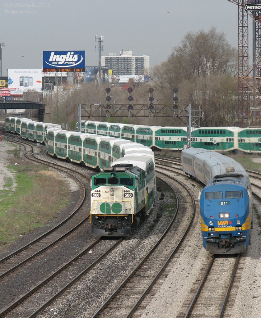 Don't believe your eyes, there's actually 4 trains here. A morning at Bathurst Street bridge finds:  1) Part of a GO train in the background using the rarely-used connector track, to get from the Galt Sub/Weston Sub side to the Oakville Sub side in order to head west to GO's Willowbrook maintenance facility in Mimico. 2) VIA 911 with equipment off #90, backing to VIA's Toronto Maintenance Centre from Union Station. 3) GO 560 on a not-in-service train, snaking through the switches onto the main as it heads back to Willowbrook . 4) And GO 561's train, whose unit is nearly invisible because it's coupled to the end of 560's train, leading the trip west.  For those wondering about the billboard, the Inglis sign's inspirational quote of that day: "Take to heart only / Those things that / Make you stronger"