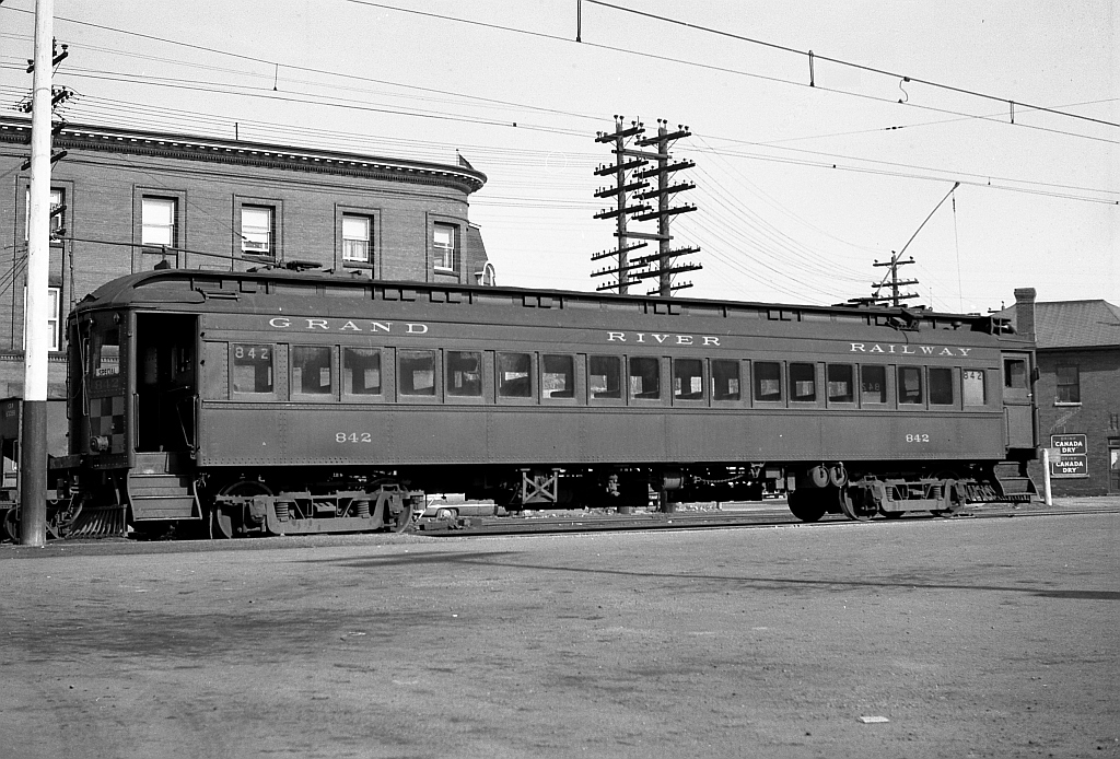 Visible here is a broadside image of Grand River Railway car 842, the fantrip's car, taken at the GRR - LE&N Galt Main St Station.  As mentioned in a previous photo, the brick and stone station was built during the summer of 1922 and opened for passenger service on December 23rd, 1923. The location was on east Main Street, opposite the then standing CPR Freight shed. The location, thus allowed both railways to operate their passenger rail equipment interchangeably as electrical voltage was made consistent between both railways on December 4th 1921. The location became Mile Post Zero for both railways. The GRR to the north, the LE&N to the south. Later it became a loading point also for the bus service of Canadian Pacific Transport that served Preston, Blair and Kitchener. The building was demolished in the summer of 1956.  Car 842 was part of eight steel passenger cars built by the Preston Car & Coach Company in 1921 when the GRR upgraded from 1500 to 600 volts. In the years following the end of passenger service in 1955, most were eventually scrapped.  Photo taken by Cecil Hommerding, from the collection (Copyright) of Doug Leffler. Substantial caption information provided by George Roth et al with much thanks. Some car details from the late W.E. Miller's Grand River Railway site  Other photos from that day: The GRR-LE&N Galt Station: http://www.railpictures.ca/?attachment_id=10502 Car 864 at Galt Station: http://www.railpictures.ca/?attachment_id=10412 Fantrip car 842 at Kitchener: http://www.railpictures.ca/?attachment_id=10681  For more details on Cecil, see here.