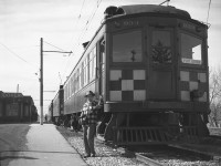 Lake Erie and Northern car 933 is shown coupled to two other cars at Port Dover station. The gentleman posed by 933 is a good friend of Mr. Hommerding, Jim Findlay of Hudson, Michigan, who attended the fantrip with Cecil and is seen snacking on an ice cream bar. <br><br>Car 933 would be a “protect service” car that was kept at the Port Dover Station to cover any needs of service. Port Dover was the south end of the LE&N line that started at the GRR-LE&N Galt Main Street station and ran 51 miles south to Port Dover. The station was built in 1947 to a CPR Station Plan, at Chapman and Main Street, Milepost 51.0 of the LE&N. It was sold in 1965 to CN, who later sold it to the local town. Today it is leased to a private firm, owned by the Norfolk Region and still exists today (though not like it looks in this 1950 photo!). <br><br> This series of photos were taken by a now-deceased friend, William Cecil Hommerding (who passed away in 1983). Another mutual (deceased) friend, Jim Findlay of Hudson, Michigan (pictured) accompanied Cecil on the trip. The Buffalo, Rochester and Syracuse chapters of the NHRS did each run several one day trips over the entire near 69 mile GRR-LE&N line around when these photos were taken, always on a Sunday. This particular trip was by a group from Michigan who held a one day, full length of the line trip on April 30th 1950 using GRR car 842, as pictured in many of Cecil's images. Although both Cecil and Jim are now deceased, their photos live on! <br><br> (<i>* Editors note: we would like to thank Doug Leffler for sharing these excellent historical photographs of Cecil's with us, and George Roth for helping interpret much of the historical and contextual information depicted in these photos.</i>) <br><br> <i><u>Other photos from the fantrip:</u></i><br> Car 842 crossing the bridge at Waterford: <a href="http://www.railpictures.ca/?attachment_id=10357"><b>http://www.railpictures.ca/?attachment_id=10357</b></a><br> The fantrip at Kitchener: <a href="http://www.railpictures.ca/?attachment_id=10681"><b>http://www.railpictures.ca/?attachment_id=10681</b></a><br> The GRR's Preston Shops: <a href="http://www.railpictures.ca/?attachment_id=10413"><b>http://www.railpictures.ca/?attachment_id=10413</b></a><br> <br> <i>For more details on Cecil, see <a href="http://www.railpictures.ca/?attachment_id=10297"><b>here</b></a>.</i>