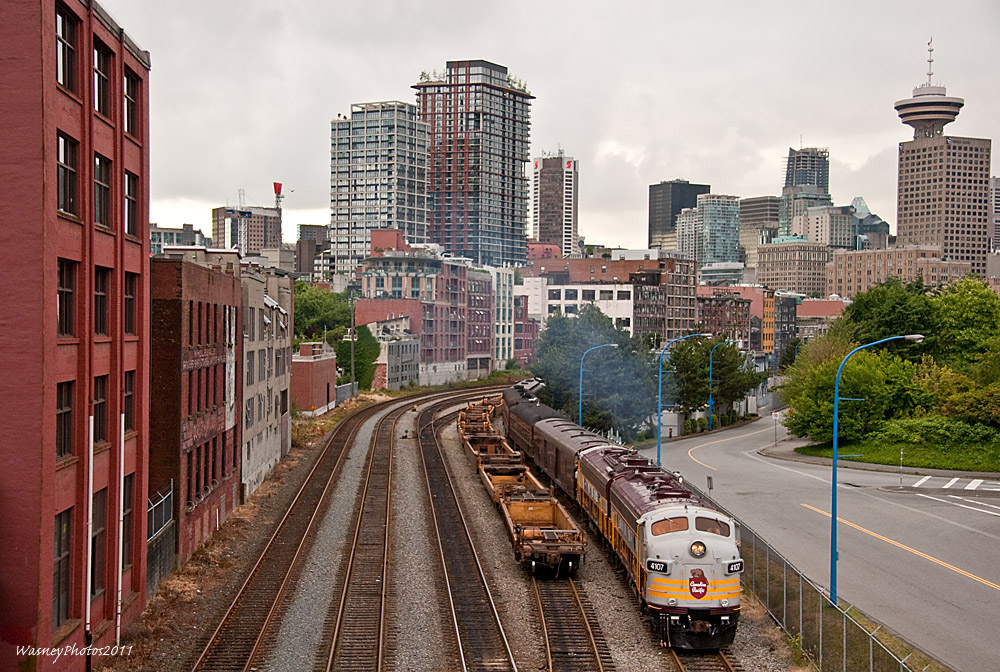 During the Summer of 2011, CPs Royal Canadian Pacific equipment made a trip to Vancouver, BC for some special runs to mark the anniversary of the first train to arrive at Port Moody. Over two evenings, seperate employee-only dinner charters were run between Vancouver Waterfront and Mission, BC. On July 7, 2011 the City of Vancouver towers above as the train departs CPs N Yard.