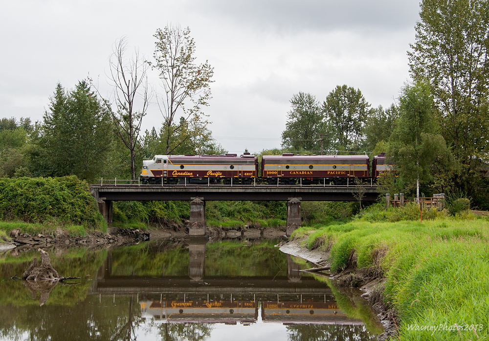 Returning westbound from Mission, BC, CPs heritage train crosses over Kanaka Creek in Maple Ridge BC. Despite the grey weather the winds managed to keep away, allowing for a nice reflection.
