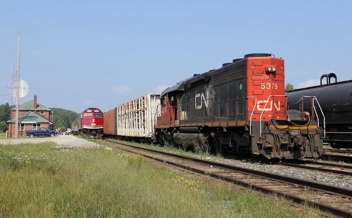 Algoma Central... CN 2575 + CN 2143 have a 24 car train 573 tucked away in track 3 (to depart a short while later as 571) ; CN 5379 is front coupled with 3 loaded log cars ; and the tri weekly passenger, train 632 makes its station stop.