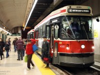 It's all hustle and bustle at Spadina Subway Station's streetcar platforms: passengers disembark 510 Spadina cars for trains on the nearby Bloor-Danforth and Yonge-University-Spadina subway lines, cars unload and load waiting passengers, a supervisor attends to his duties, and the operator of TTC CLRV 4005 adjusts his sign for the run back down Spadina.