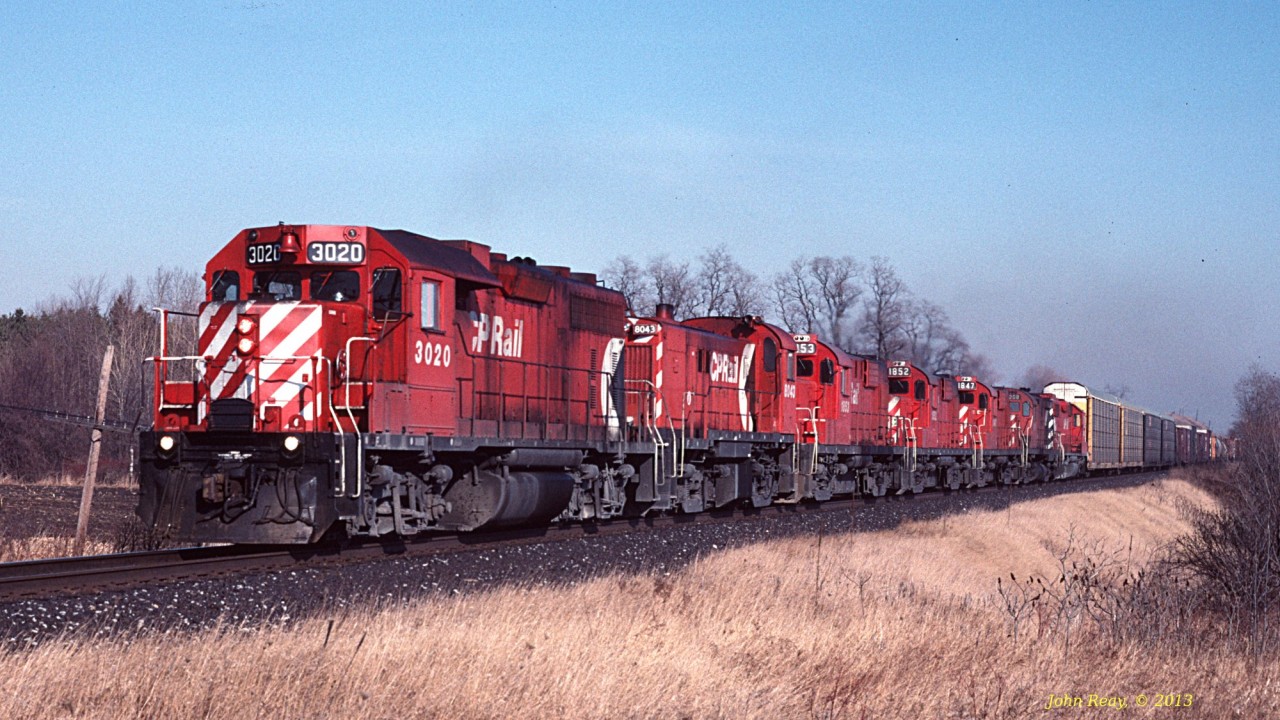 CP GMDD GP38 #3020 leads an assortment of 4-axle MLWs (including RS-18u's, C-424's and a lone RS-23) westbound at Stacey Road, Hope Township in March 1991.