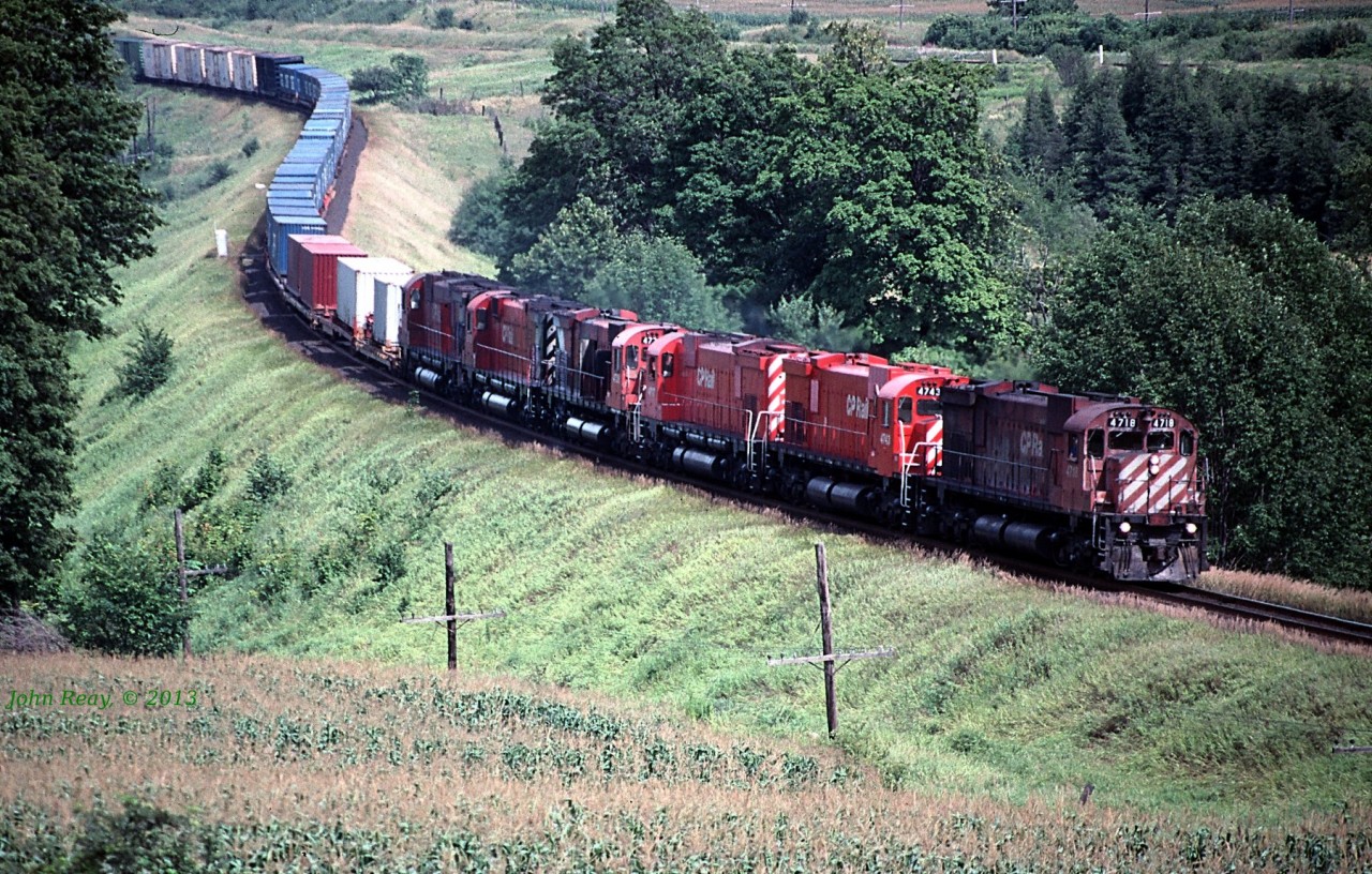 Six CP 6-axle MLWs led by M-636 #4718 round the S-curve at MP 151 CP Belleville sub. Note the CN Kingston and Elliott Road grade crossing is near the top of the picture.