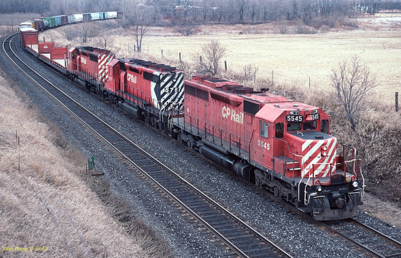 Three GMDD SD40-2s (including a "blinded" trailing only unit with full Multimark) head west under Courtice Road near the west end of Darlington siding in April 1994.